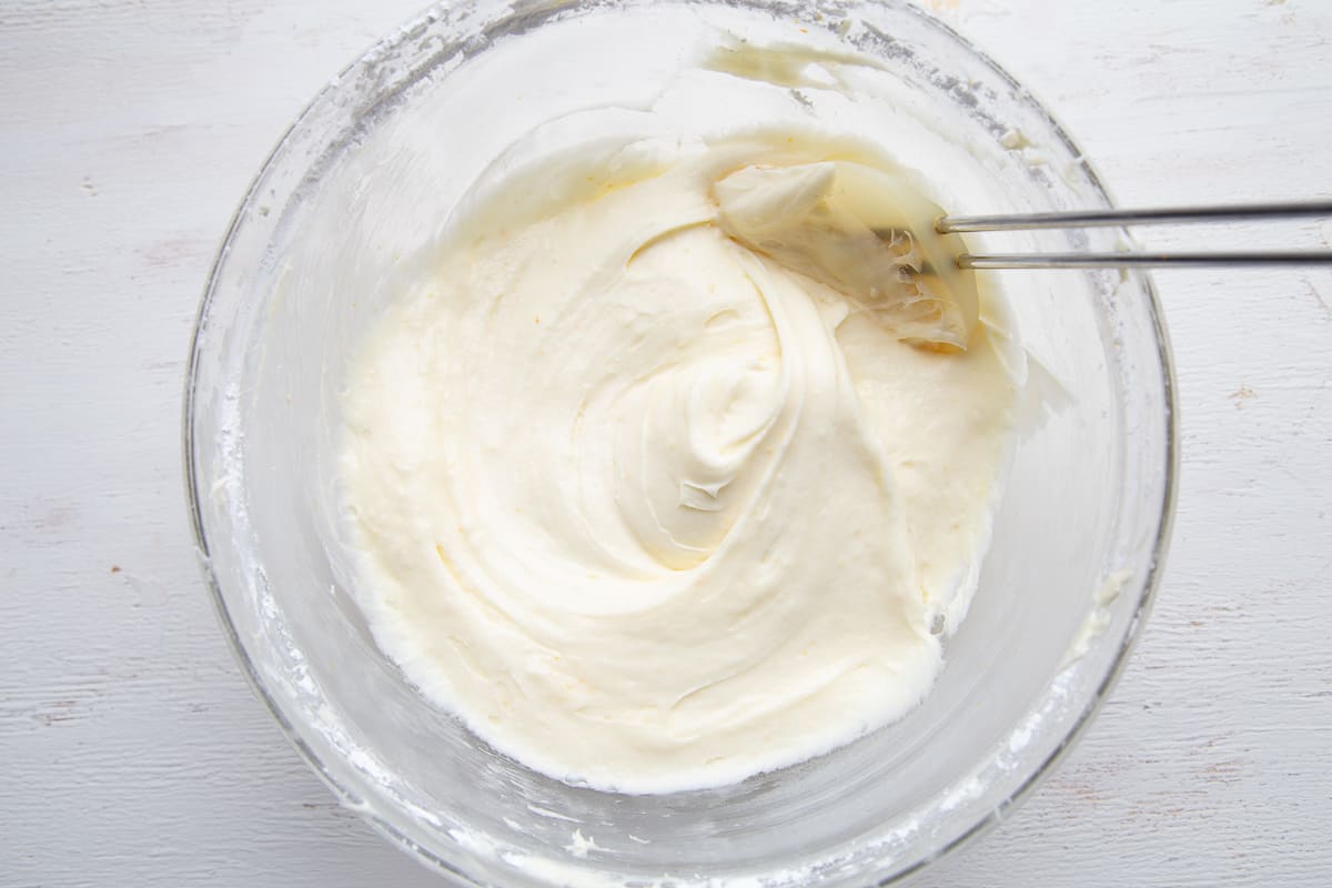 cream cheese frosting in a glass bowl with a spatula.