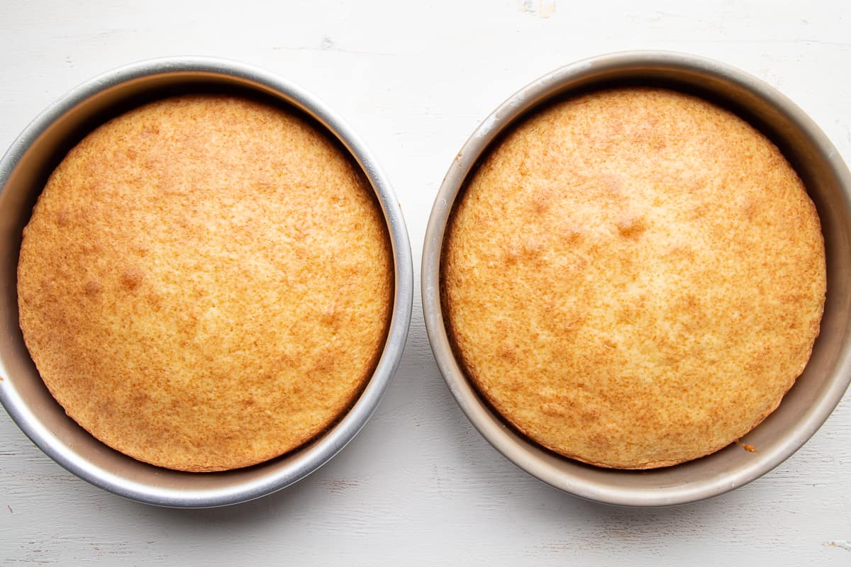 two unfrosted orange cakes in 9 inch cake pans.