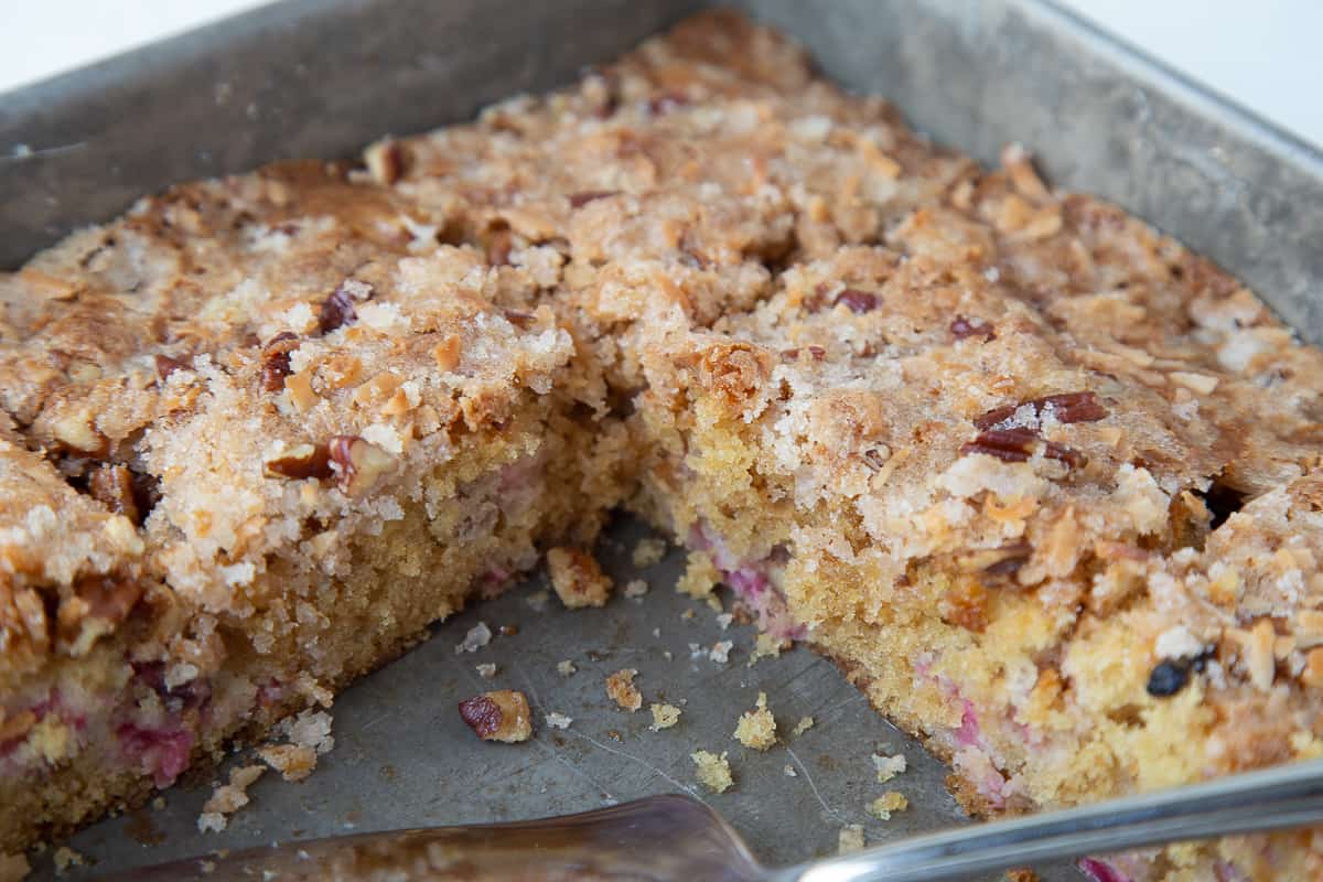 rhubarb cake in a metal pan with slices taken out.