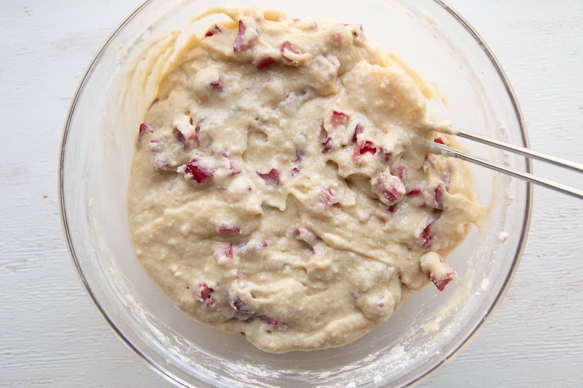 rhubarb cake batter and a spatula in a glass mixing bowl.