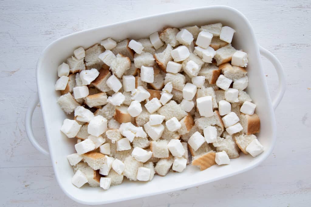 bread cubes and cream cheese cubes in a casserole dish.