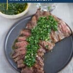 skirt steak on a gray plate, topped with chimichurri.