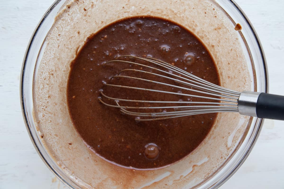 brownie batter and a whisk in a glass bowl.