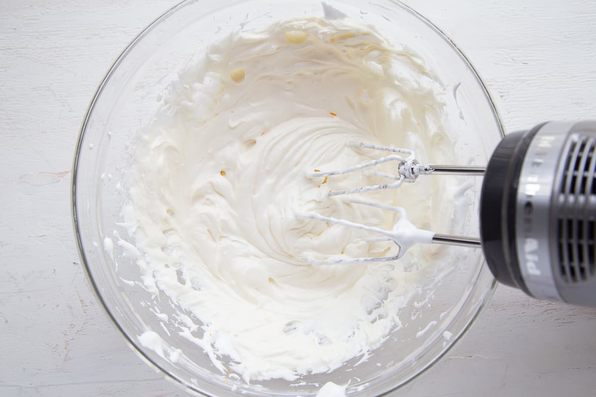 fruit dip in a glass bowl with a hand mixer.