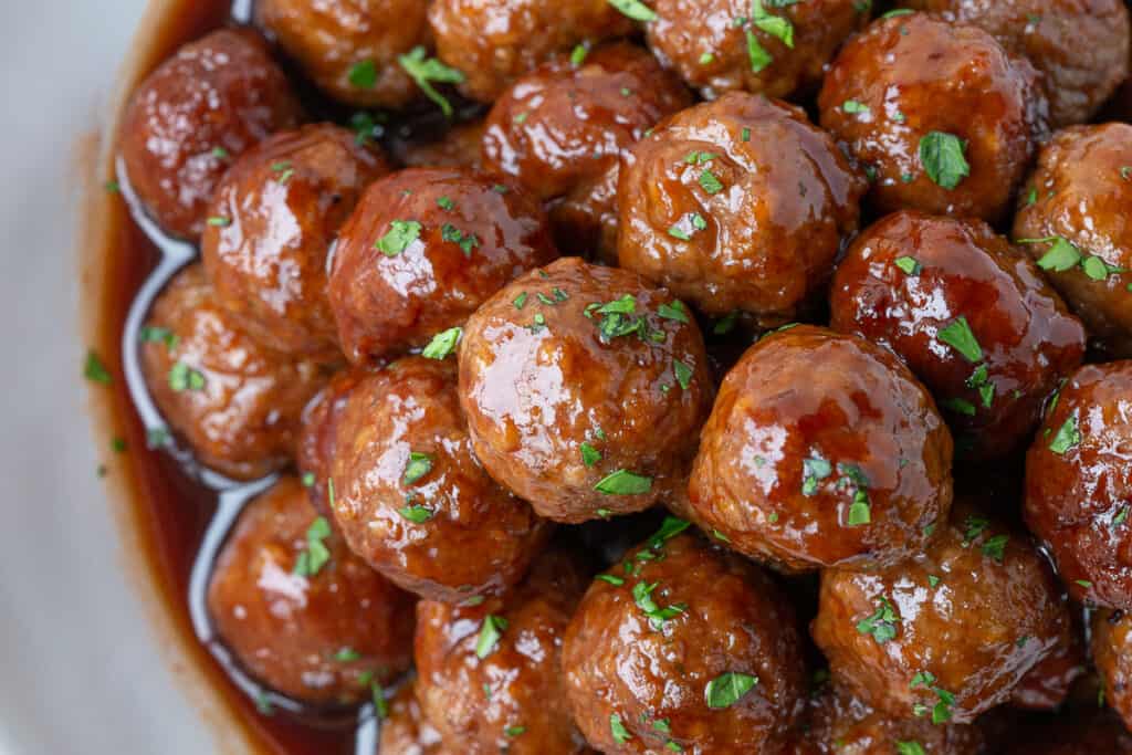 close up of crockpot bbq meatballs on a white platter.