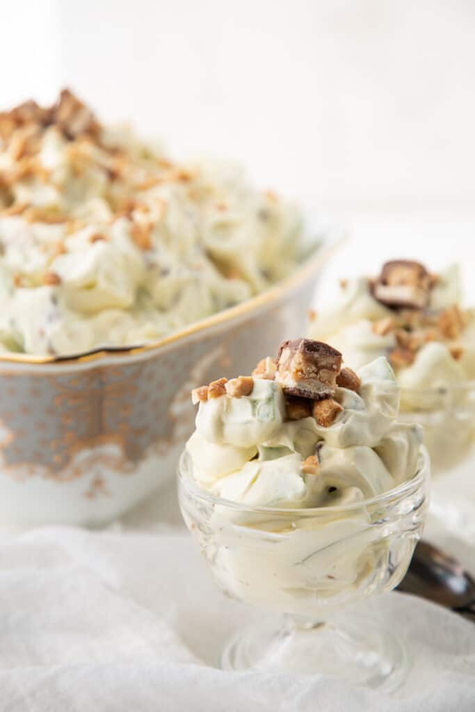 snickers salad in a large bowl, surrounded by small glass dishes of snickers salad.