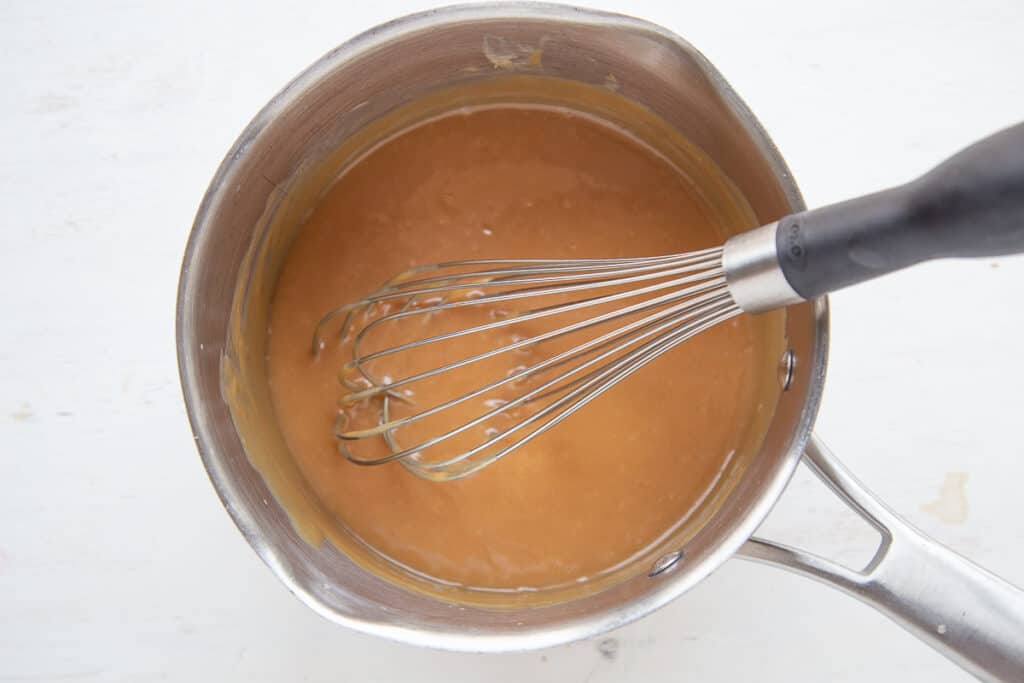 caramel in a saucepan with a whisk.