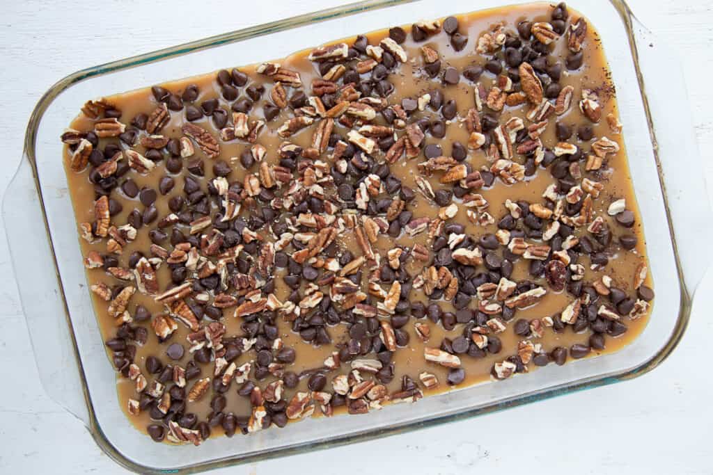 caramel, chocolate chips, and pecans in a glass baking dish.