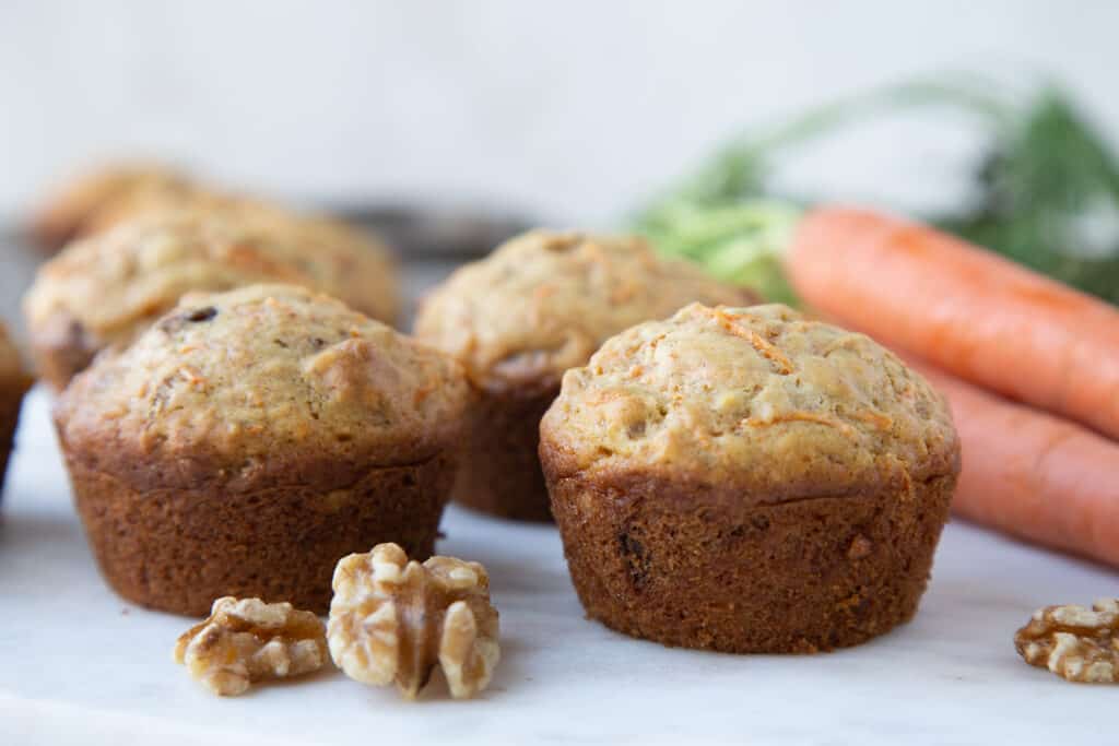 carrot muffins on a white tray with walnuts and whole carrots.