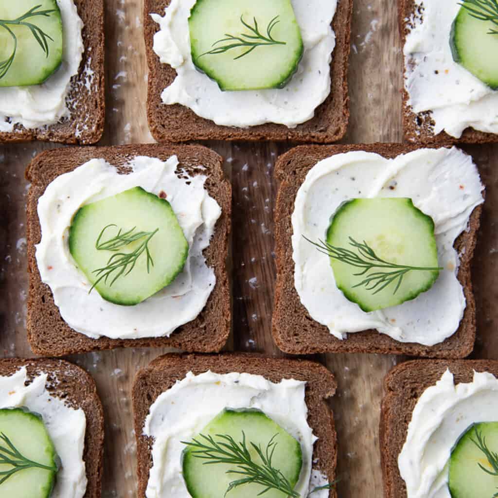 open faced mini cucumber sandwiches on pumpernickel, topped with a dill sprig.