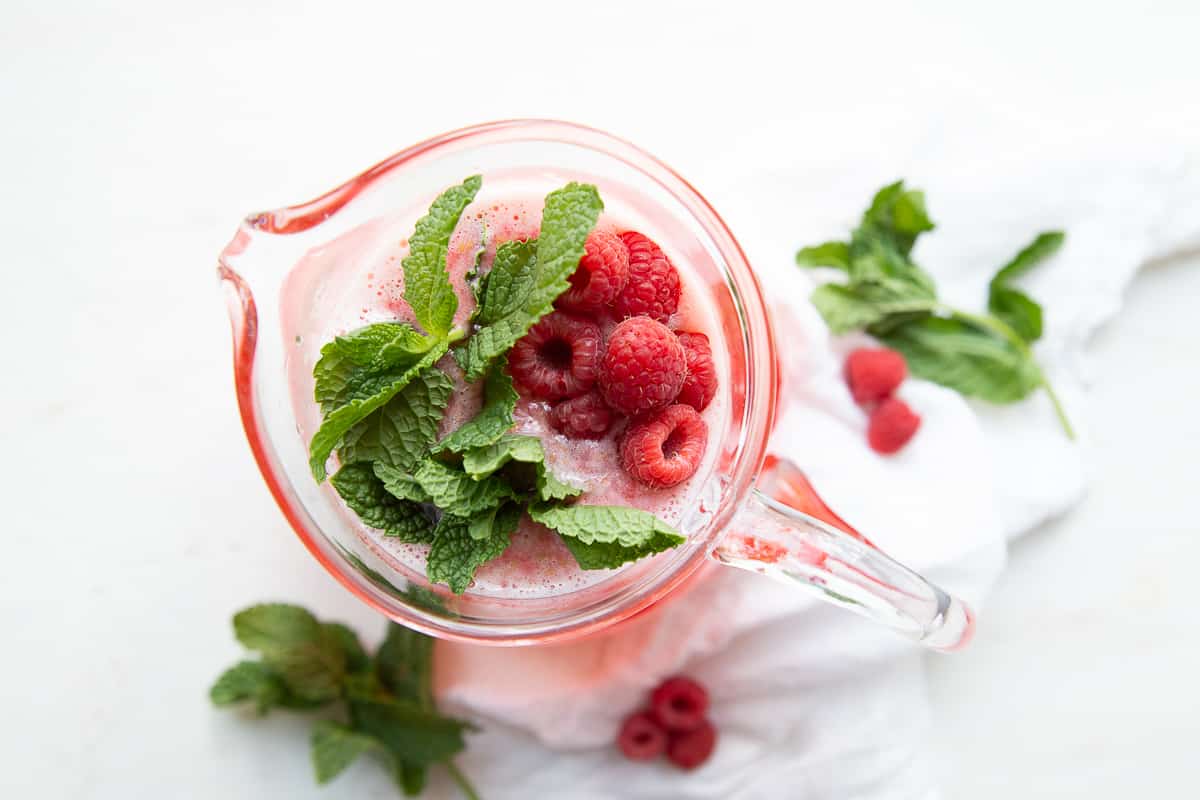 pitcher of raspberry lemonade with fresh raspberries and fresh mint.