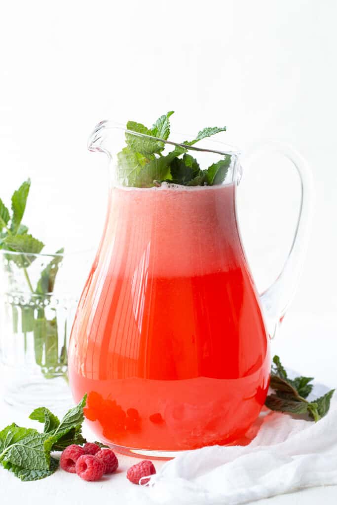 pitcher of raspberry lemonade garnished with fresh mint.