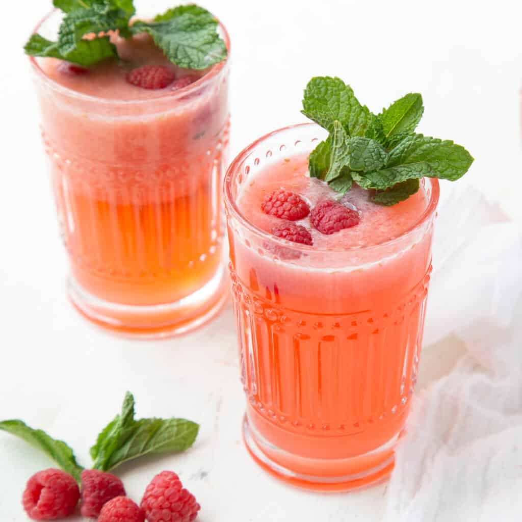 two glasses of raspberry lemonade garnished with fresh mint.