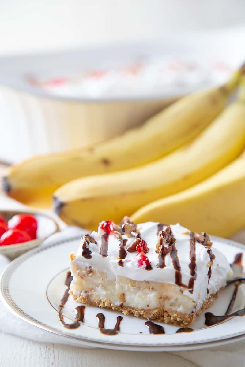 slice of banana split cake next to a bunch of bananas.