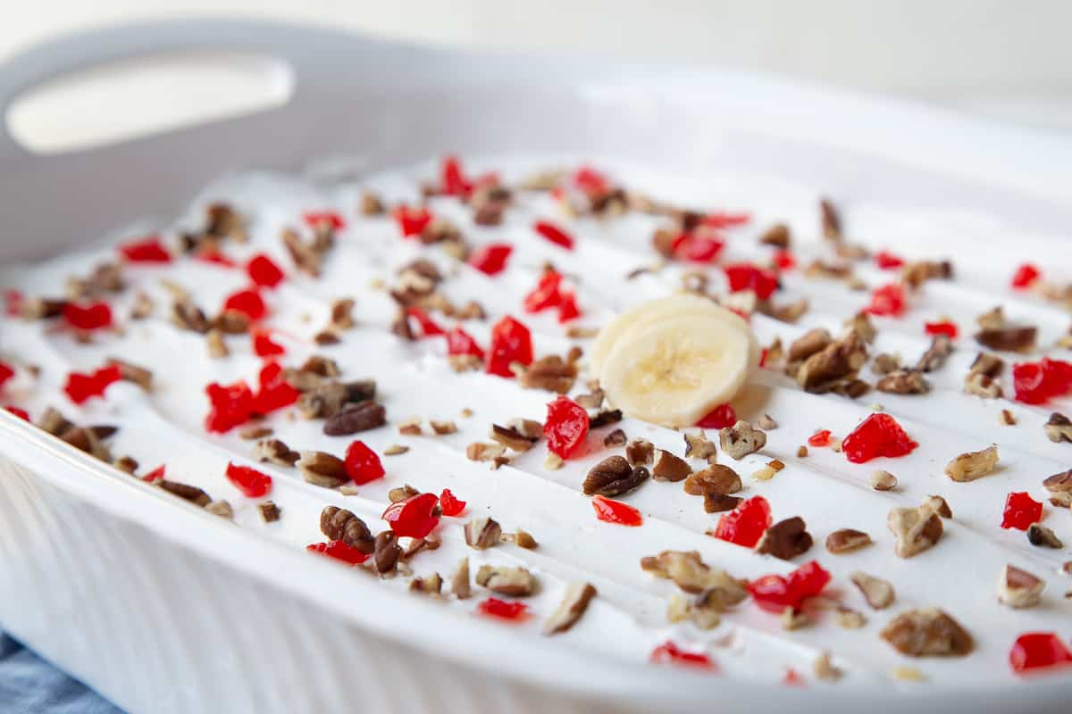 banana split cake topped with pecans and cherries.