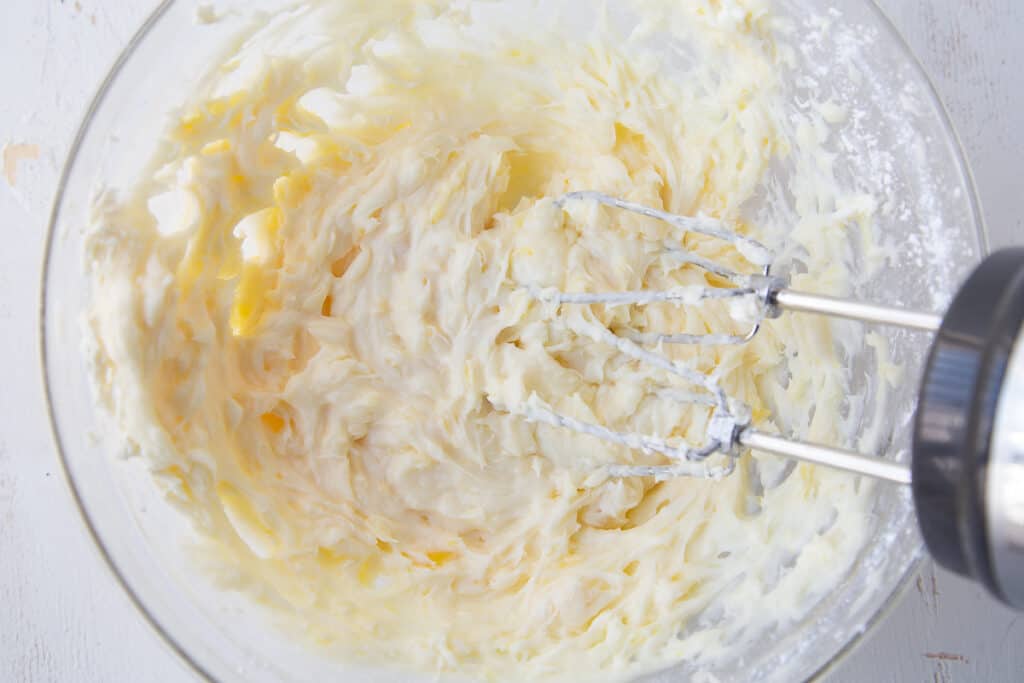 cream cheese mixture in a glass bowl with a hand mixer.
