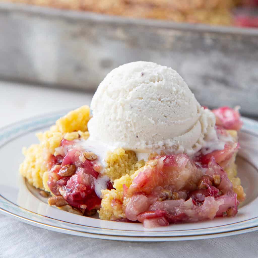 cherry dump cake topped with vanilla ice cream on a white plate.