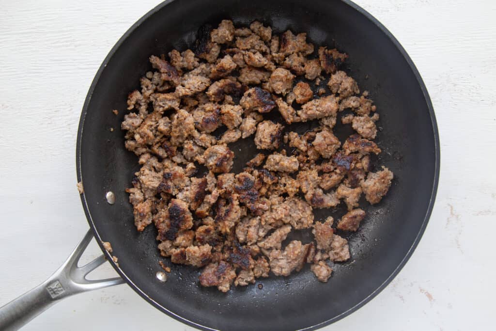 cooked sausage crumbled in a skillet.