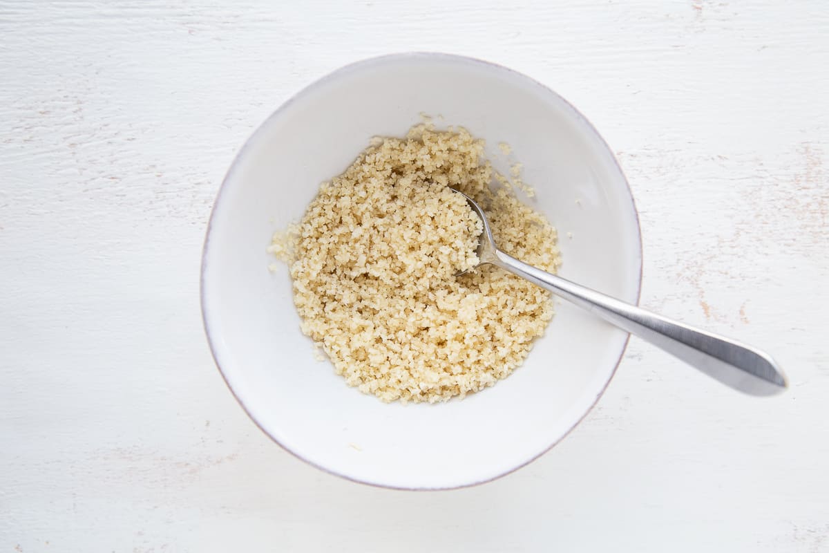 breadcrumb mixture in a white bowl with a spoon.