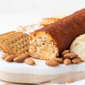 cheese roll on a marble board with crackers and almonds.
