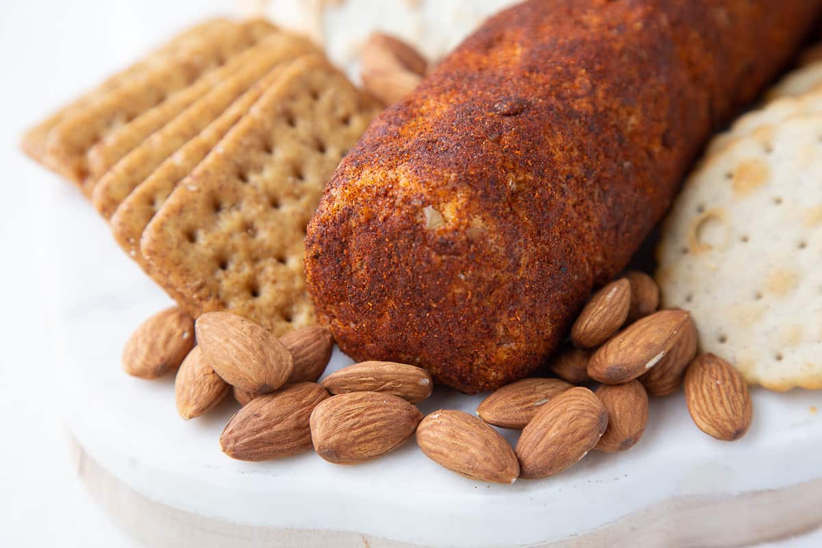 cheese log coated in chili powder next to almonds and crackers.