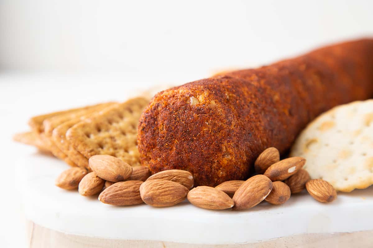 cheese roll on a white platter with almonds and crackers.