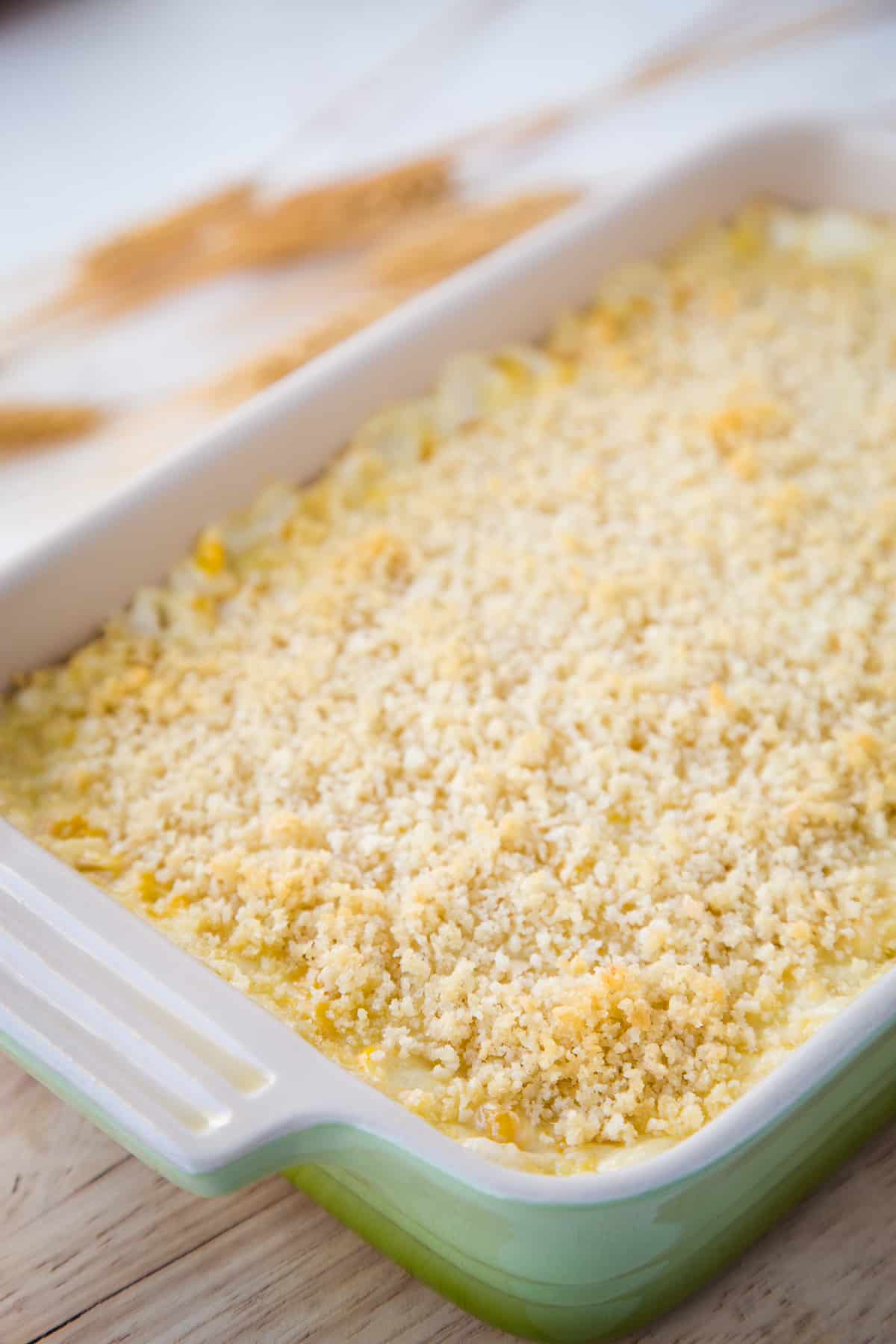 cheesy corn casserole in a green casserole dish.