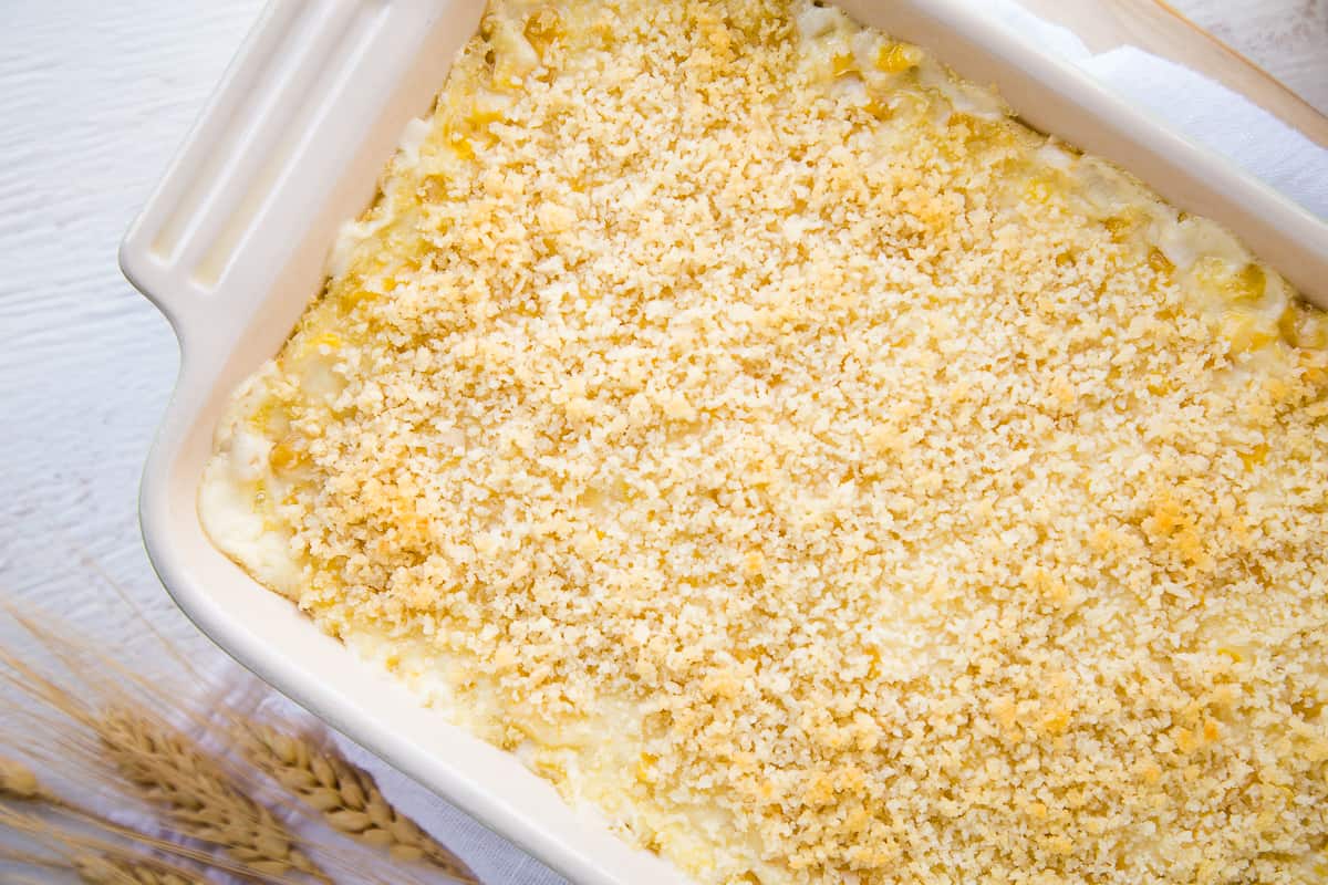 corn casserole with breadcrumbs in a white casserole dish.