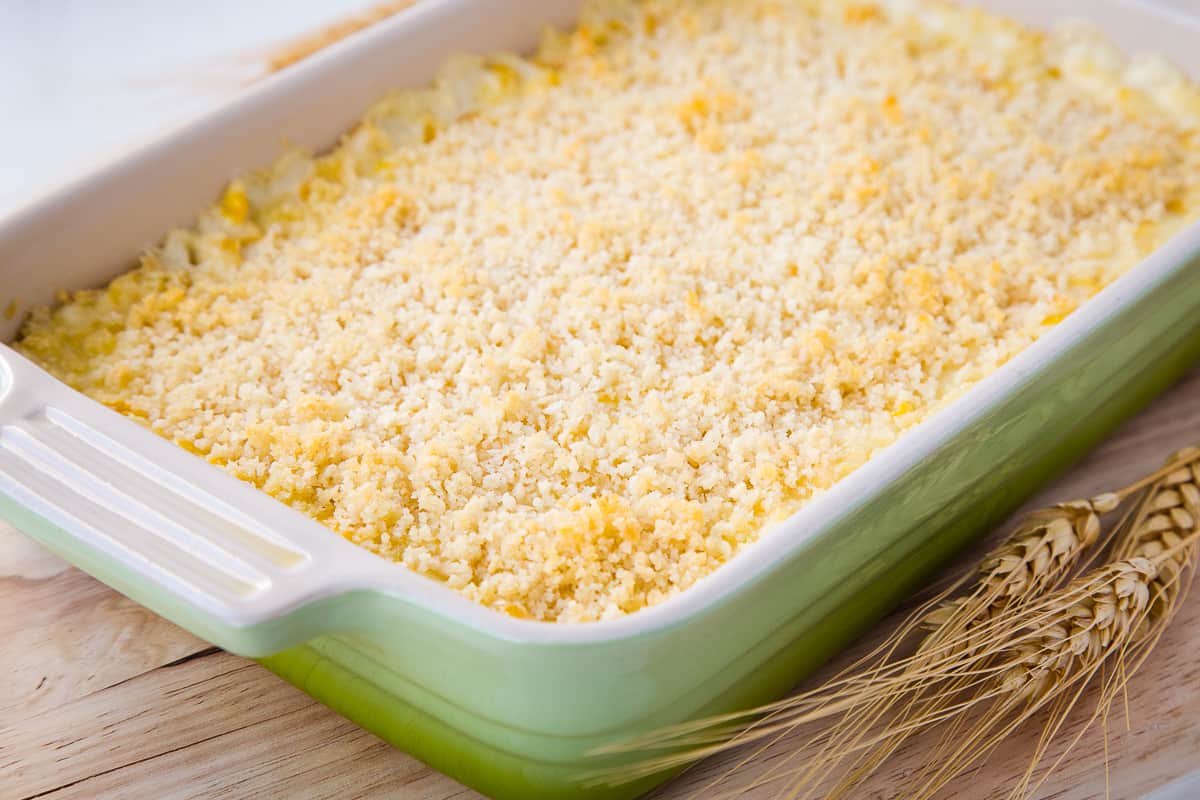 green casserole dish filled with cheesy corn casserole.
