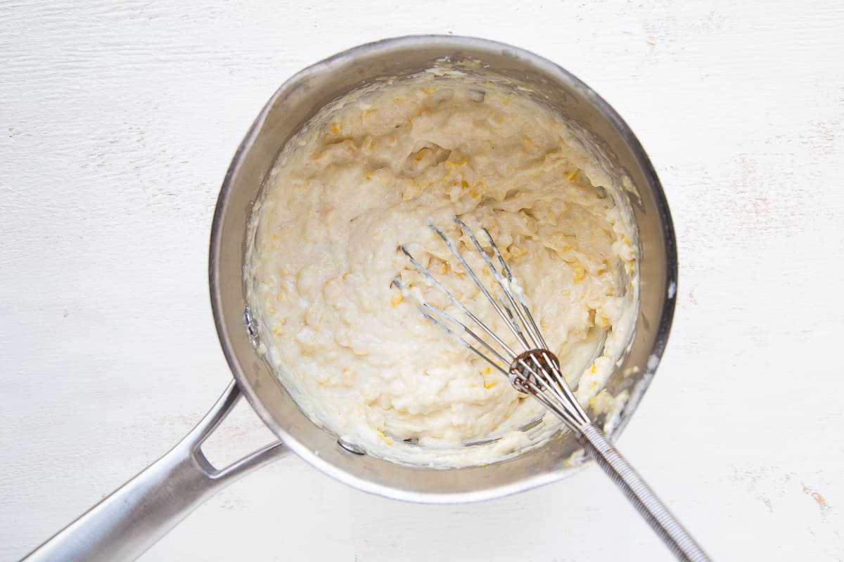 cream cheese and corn in a saucepan with a whisk.