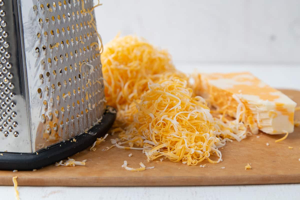 shredded colby jack cheese next to a box grater.