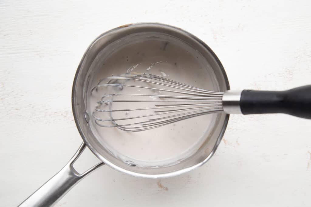condensed soup and a whisk in a saucepan.
