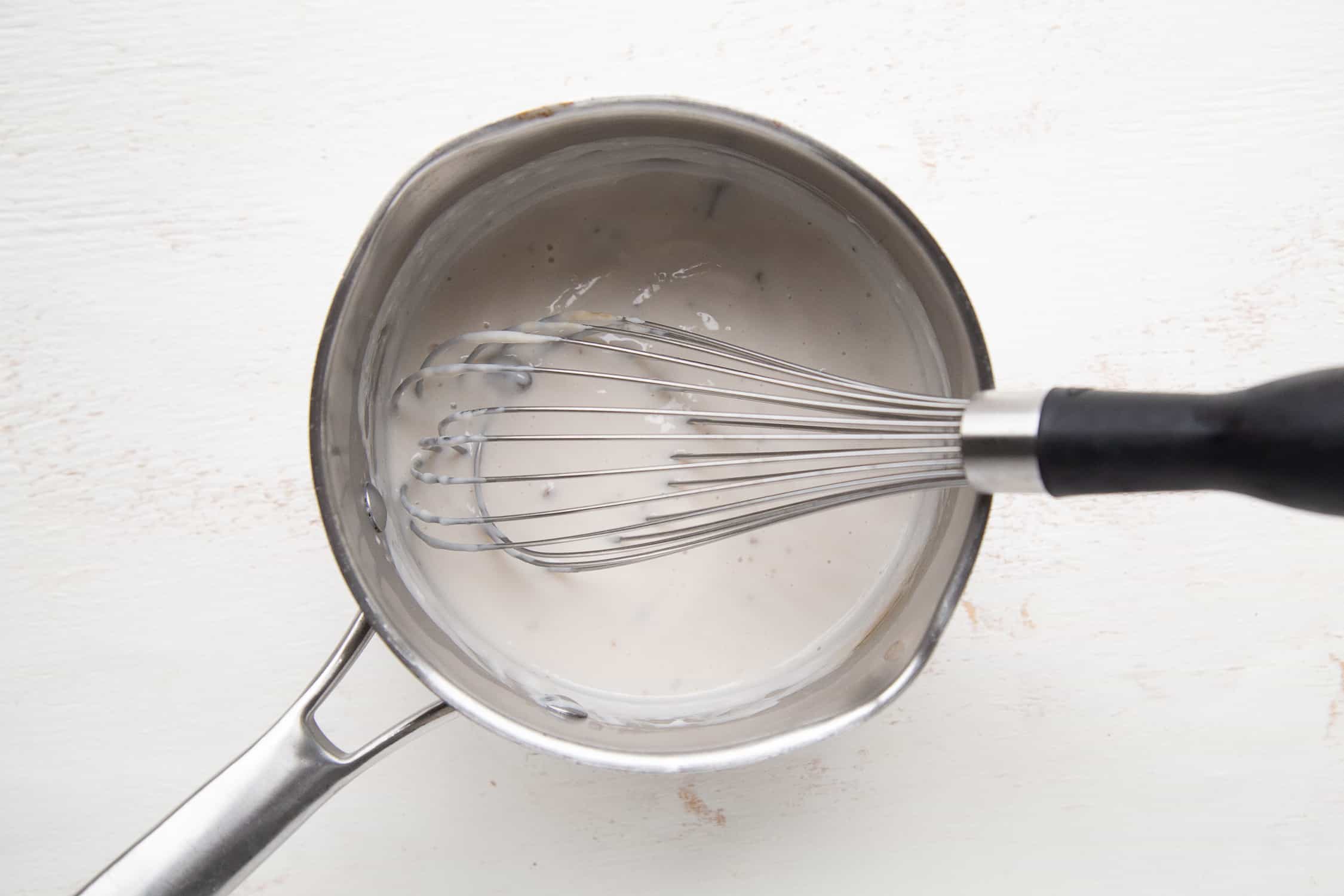 condensed soup and a whisk in a saucepan.