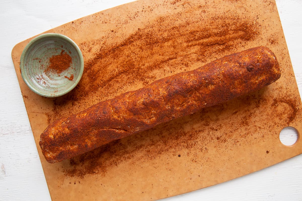 cheese roll being rolled in chili powder.