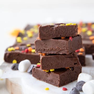 stack of marshmallow fudge squares next to chocolate chips and mini marshmallows.