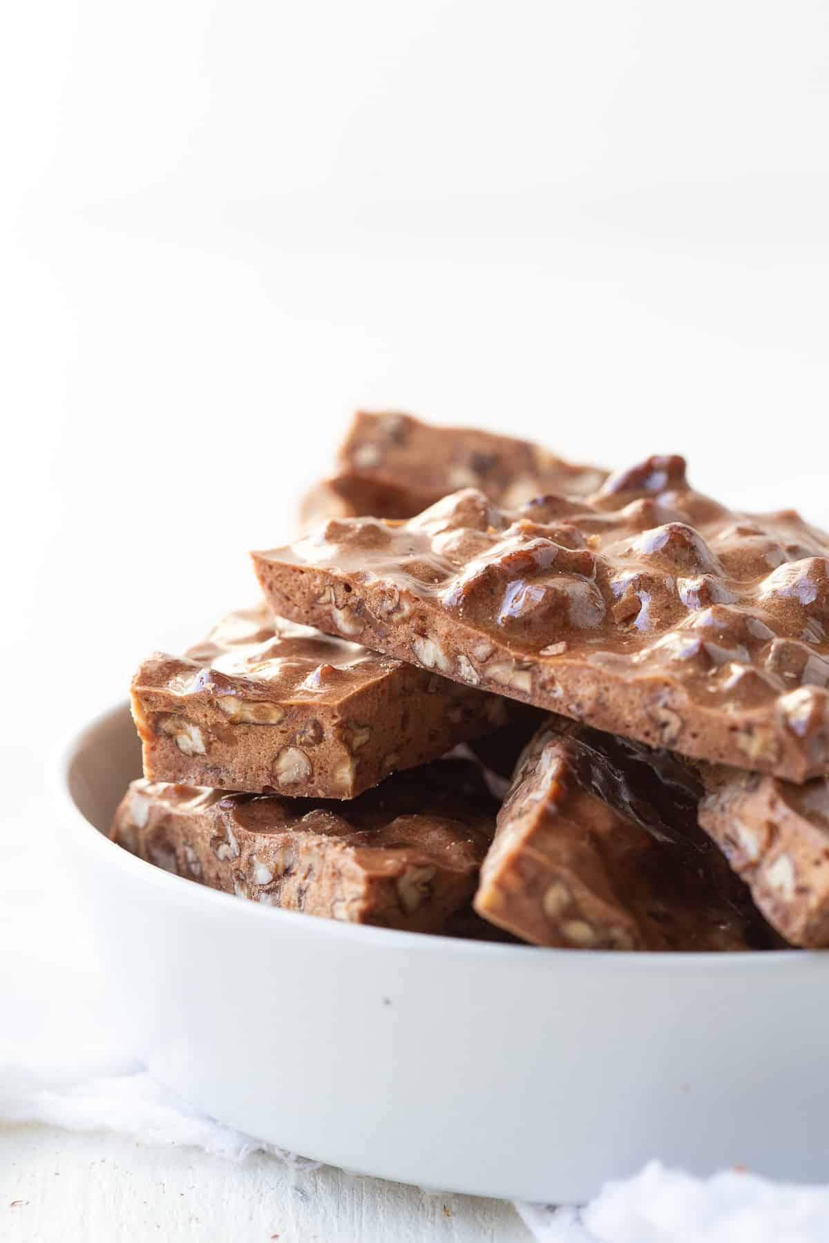 pecan brittle stacked in a white candy dish.