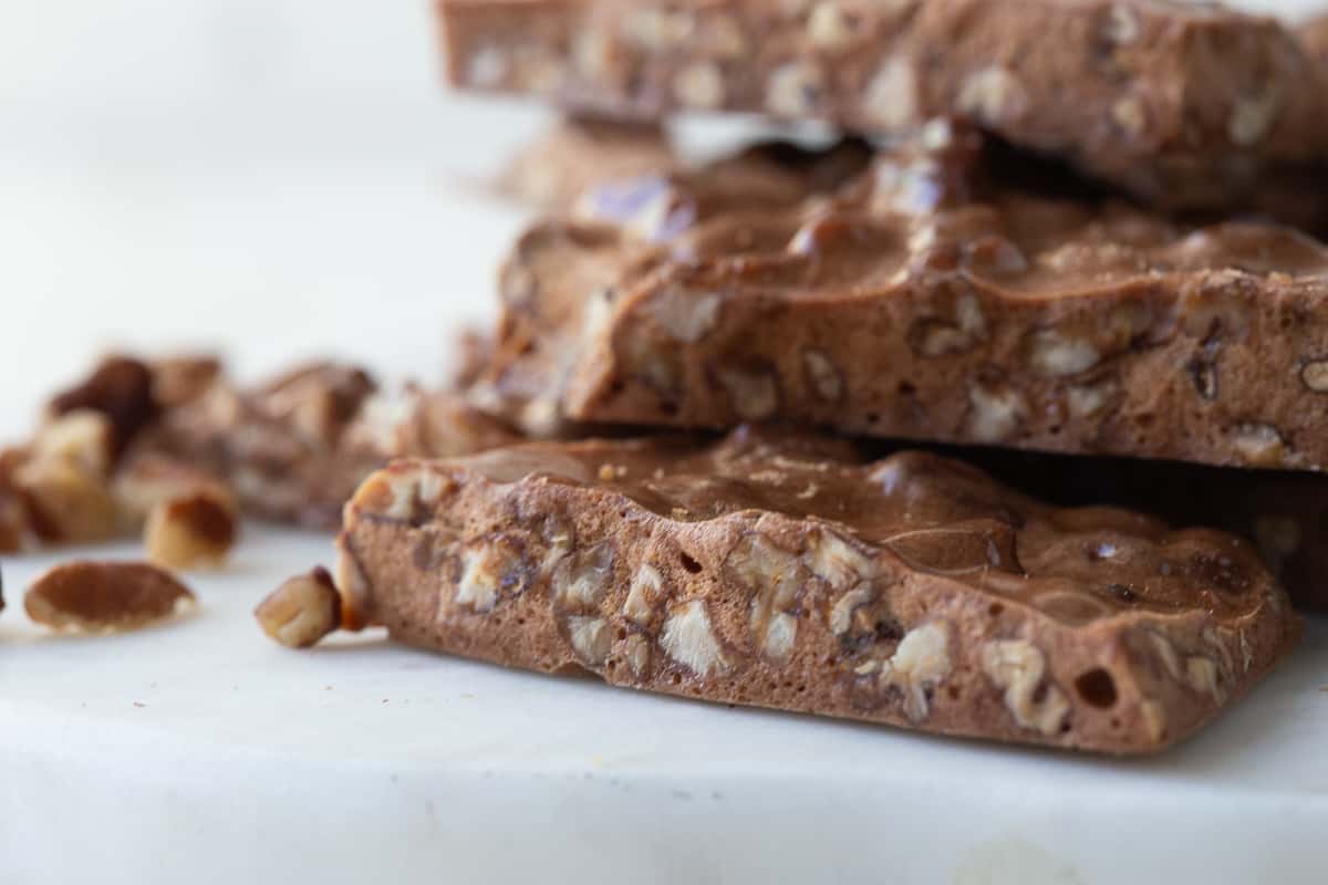 close up of pecan brittle, stacked on a white platter.