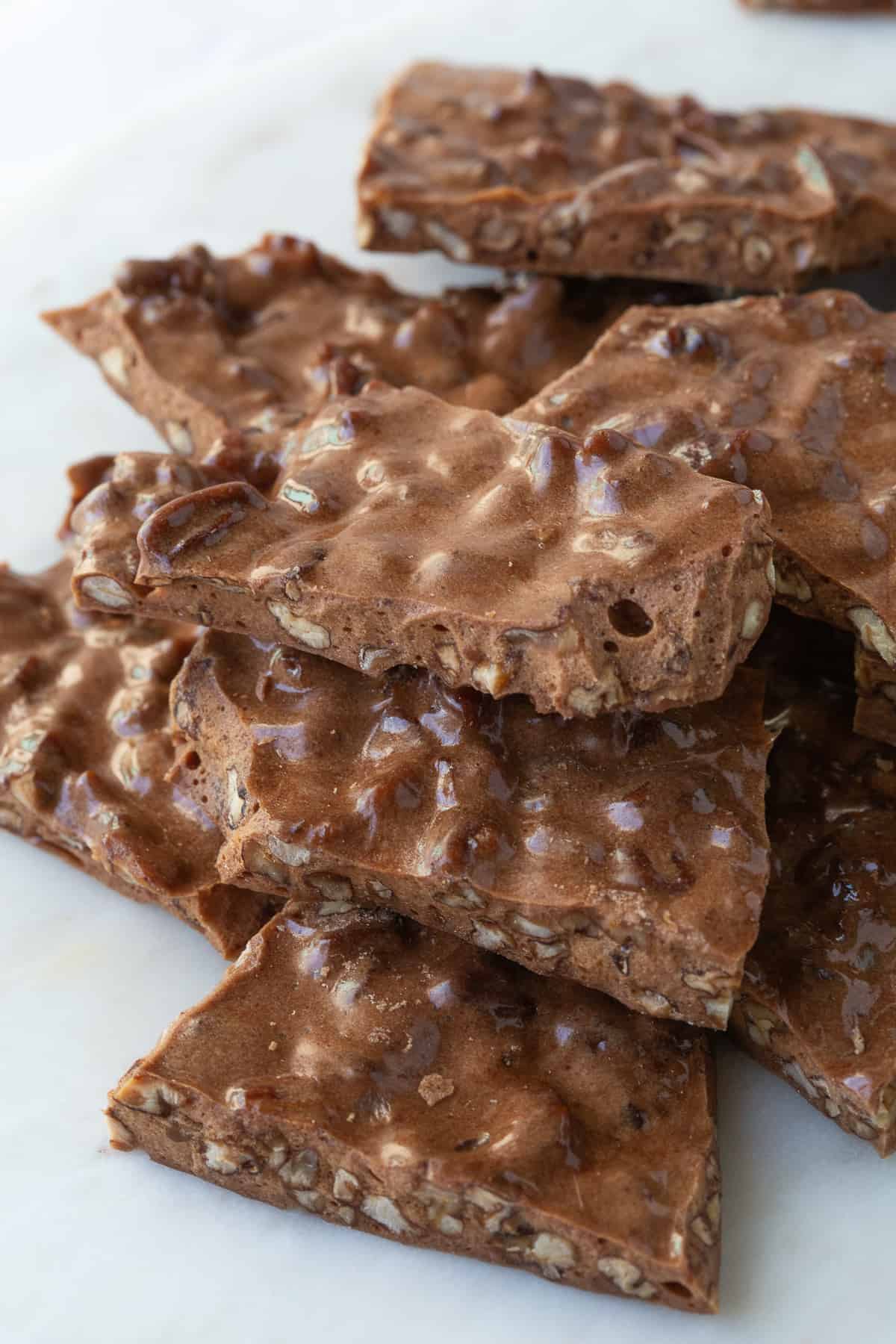 pile of pecan brittle on a white marble platter.