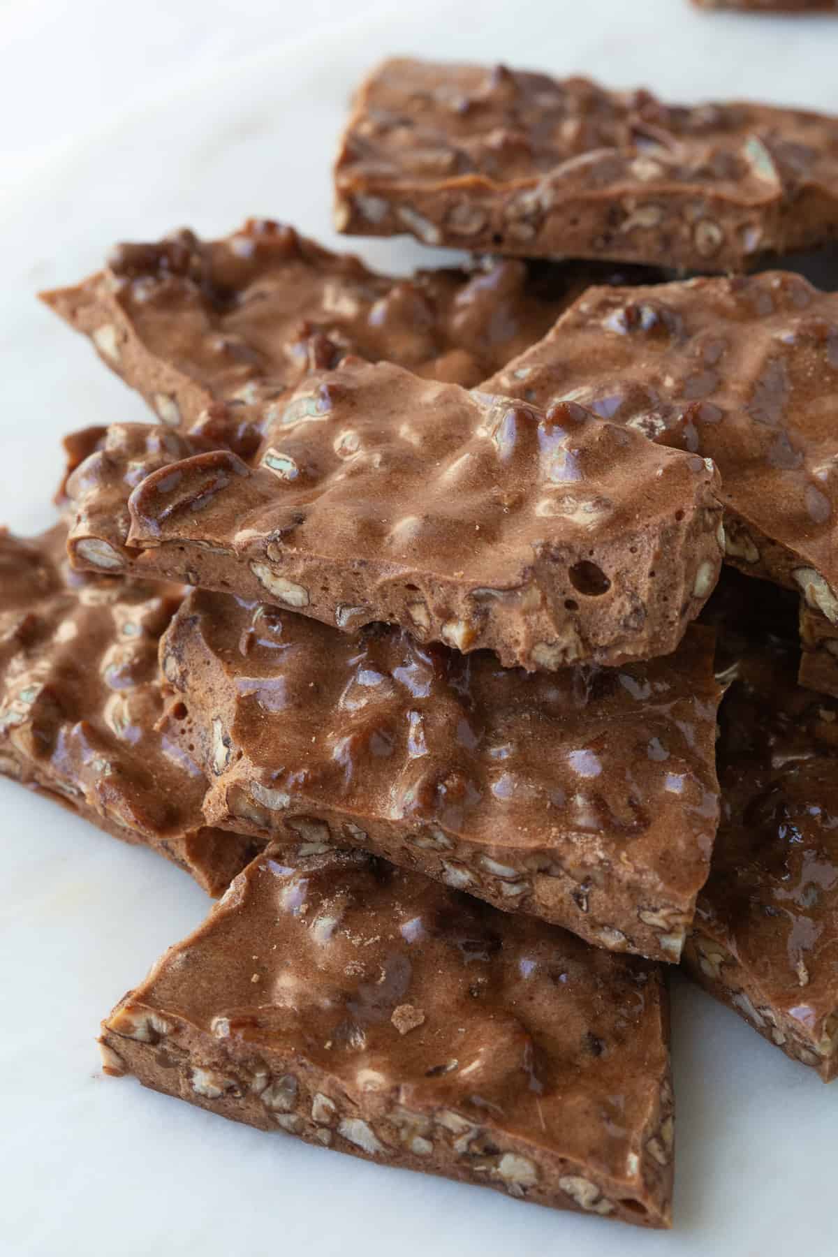 pile of pecan brittle on a white marble platter.