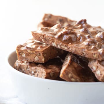 pecan brittle stacked in a white dish.