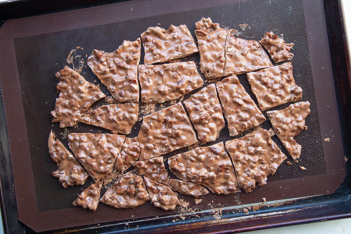 pecan brittle broken into pieces on a baking sheet.