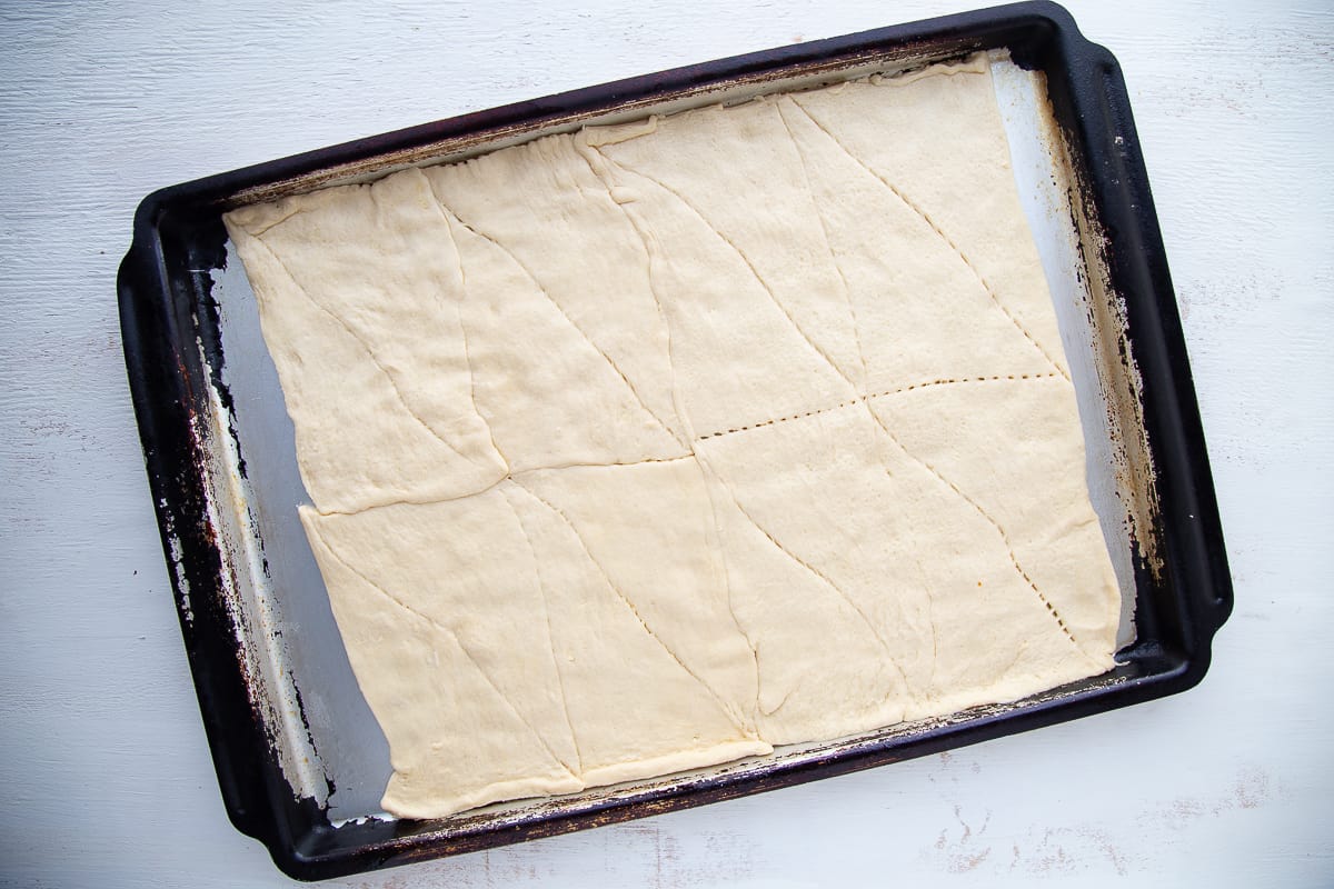 uncooked crescent roll dough on a sheet pan.