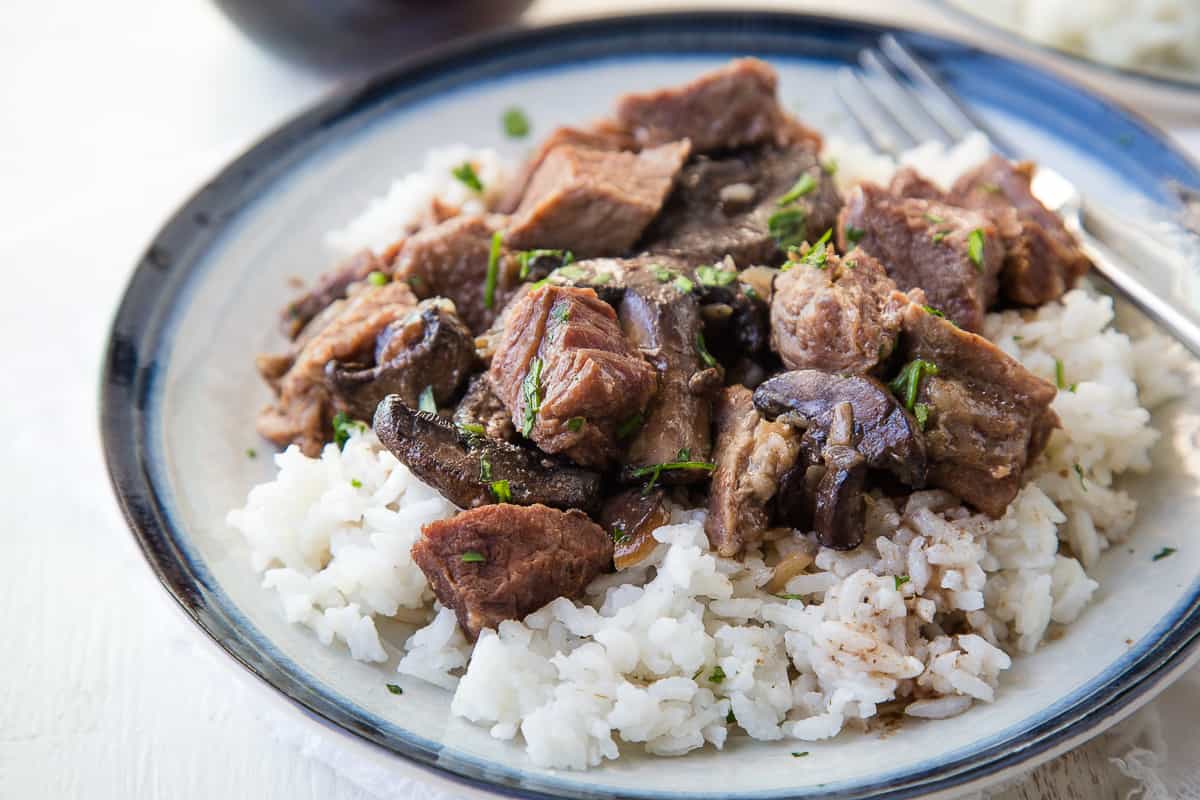 crockpot beef stew with mushrooms on a blue and white plate.