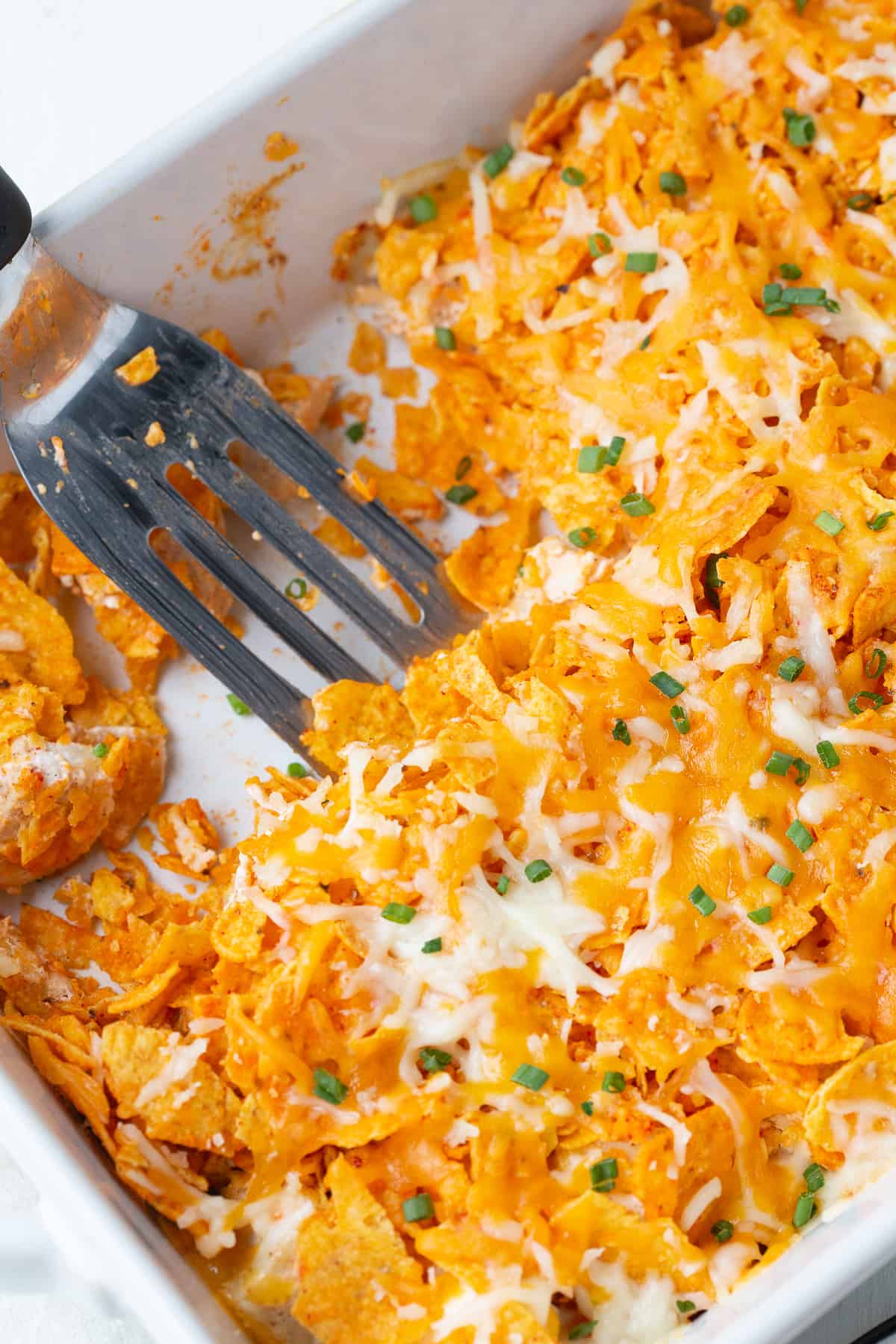 spatula in a white casserole dish with easy dorito chicken casserole.