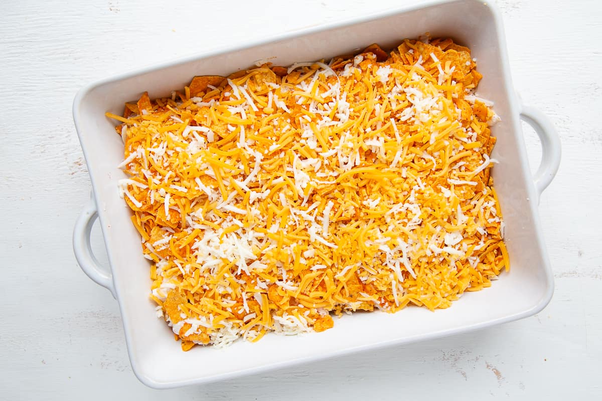 uncooked easy dorito casserole in a white dish with handles.