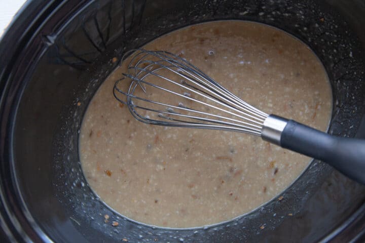 crockpot with cream of mushroom soup and onion soup mixture and a whisk.