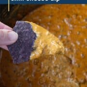 hand dipping a chip into chili cheese dip.