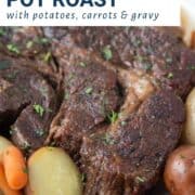 Crockpot Pot Roast on a white platter with potatoes and carrots.