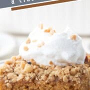 a slice of cake topped with crushed heath bars and a dollop of whipped cream.
