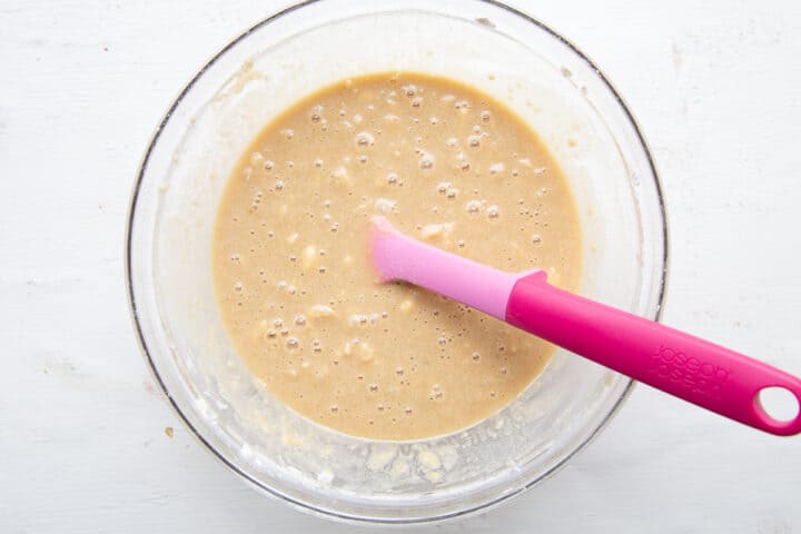 cake batter in a bowl with a pink spatula.